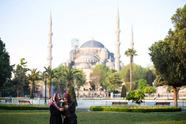 Türkiye, Istanbul-3 Mayıs 2019: Tesettür kadınlar Sultan Ahmed Camii 'nin önündeki kare parktaki telefona bakar. Mavi MOS arka planda iki Müslüman kız. restorasyon üzerinde Landmark