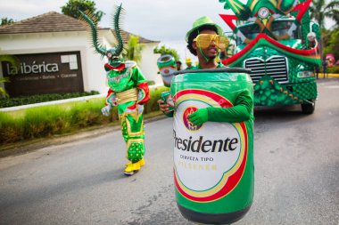 Dominik Cumhuriyeti, Punta Cana - 3 Mart 2018: Karnaval'da renkli temalı kostümlü insanlar. Ulusal renklerle boyanmış yüzler. Presidente Beer'in kostümlü bir adamı. Ana sponsor