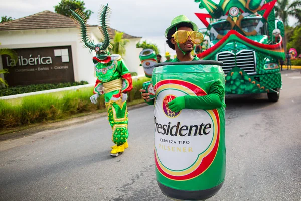Dominik Cumhuriyeti, Punta Cana - 3 Mart 2018: Karnaval'da renkli temalı kostümlü insanlar. Ulusal renklerle boyanmış yüzler. Presidente Beer'in kostümlü bir adamı. Ana sponsor
