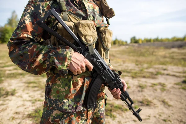 兵士は 彼の手の中に機関銃を保持し クローズアップ 黒いライフルで戦場に緑の迷彩で軍隊 — ストック写真