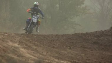 Motokros Şampiyonası'nda toprak pist yarışı. Yarışçılar hızla birbirlerini takip, kir tekerleklerin altından uçar