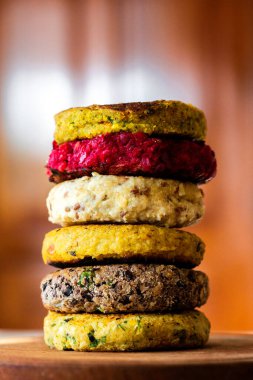 Renkli sebzeli burgerlerin yakın çekimi. Fasulye, nohut, pancar, kinoa, brokoli, tatlı patates. Vejetaryen yemekleri lezzetli ve sağlıklı. Yarı üretim ürünler pişirmeye hazır.
