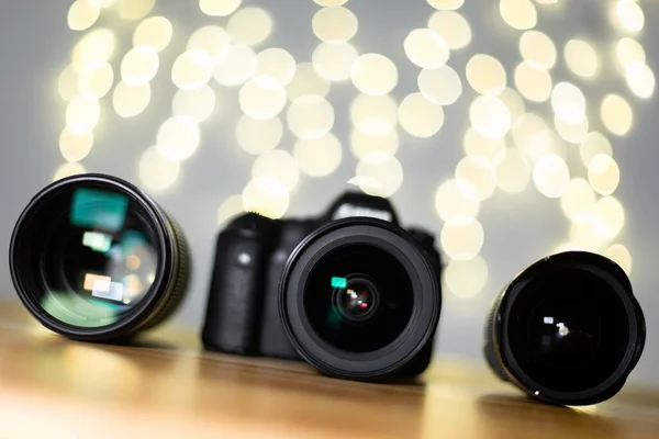 Digital camera and professional lens set on a wooden table tilted front view. Amazing photography background with yellow bokeh