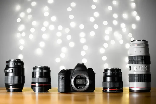 Beyaz bokeh arka planda, ahşap masada profesyonel prestijli lensleri olan montaj ve sensör dijital kamerasını aç. Fotoğraf ve video ekipmanlarının onarımı
