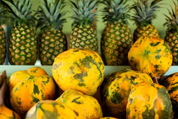 Meyveleri sulu papaya ve arka planda bir sıra ananas tropik bir taşra meyve dükkanının tezgahında.