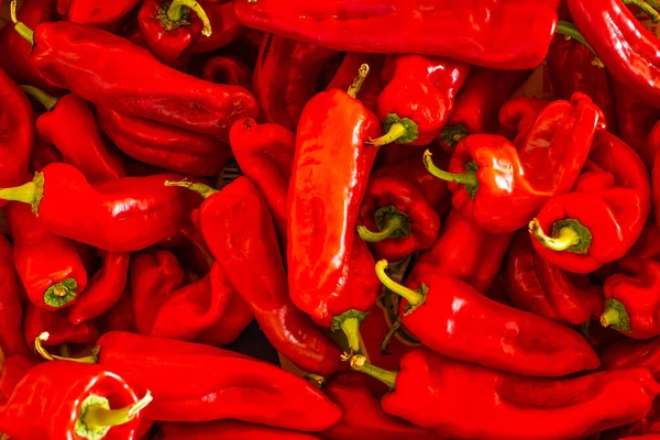 Close up of many fresh red sweet banana peppers in a street shop. Top view. Fresh fruits and vegetables copy space background