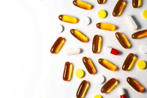 Top view of transparent tablets and colored pills scattered on white table. Pharmaceutical drug copy space minimalistic background