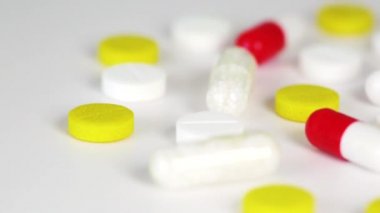 Beyaz masada dönen çok renkli ilaçların yakın çekim görüntüleri. İlaç geçmişi izole edilmiş.