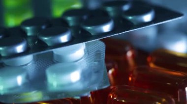 Soğuk ışıkta dönen bir sürü farklı tablet ve hapın yakın çekimi. İlaç geçmişi, sinematik görüntüler.