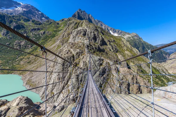 Breath taking view on the Trift bridge, a suspension bridge over the Triftsee, glacier, in Gimsel on Bernese Oberland, Switherland.