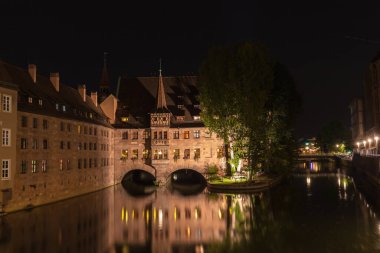 Almanya 'nın Bavyera eyaletinin Nuremberg kentindeki Pegnitz nehrindeki Heilig-Geist-Spital' in gece manzarası.