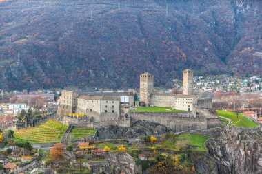 Sonbaharda Montebello Kalesi 'nin bir tepesinde bulunan renkli ağaçlar ve yeşil çimlerle kaplı Castelgrande Kalesi' nin havadan yakın görüntüsü Bellinzona, Ticino, İsviçre