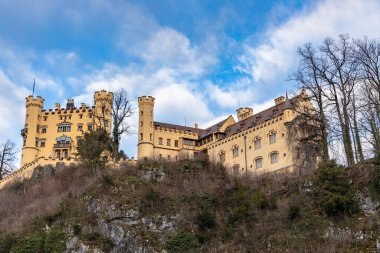 Meşhur Hohenschwangau Kalesi 'nin güzel manzarası. Kışın güneşli bir günde, mavi gökyüzü ve bulut arkaplanı, Schwangau, Bavyera, Almanya