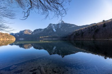Neuschwanstein ve Bavyera Alpleri 'nin arka planda, Schwangau, Bavyera, Almanya' daki Alpsee gölünün göz kamaştırıcı manzarası.
