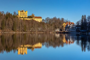 Güneşli bir günde Alpsee Gölü 'nün arka planda Hohenschwangau Kalesi ve Bavyera Alpleri' nin su, Schwangau, Bavyera, Almanya 'daki güzel yansımalarıyla göz kamaştırıcı manzarası.