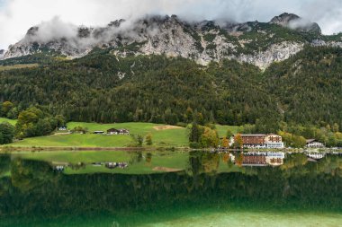 Konigssee Gölü yakınlarındaki ağaçların ve evlerin ve Alplerin güzel yansımalarıyla Hintersee 'nin Idyllic manzarası, Berchtesgaden' deki Ramsau, Bavyera, Almanya