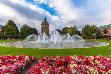 Mannheim 'daki su kulesinin (Wasserturm) güzel manzarası, önplanda renkli çiçeklerle, Baden-Wuerttemberg, Almanya