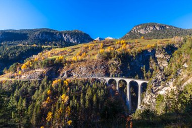 Alpler ve renkli ağaçlarla dolu bir sonbahar gününde öğleden sonra güneşli Landvasser Viaduct manzarası göz kamaştırıcı.
