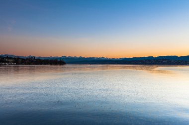 Alacakaranlıktaki Zürih gölünün güzel manzarası ve İsviçre 'deki dağ sırasındaki İsviçre Alpleri.