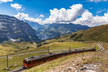 Jungfraubahn 'ın çarkıfelek treni Jungfraujoch' a doğru ilerliyor. Bernese Oberland 'daki Eigergletscher İstasyonu yakınlarındaki Jungfrau tepesinin altında güneşli bir yaz günü İsviçre' de manzarası var..