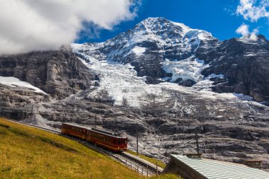 Jungfraubahn treni Monch ve Eiger buzullarının altındaki Jungfraujoch 'a doğru ilerliyor. İsviçre, Bernese Oberland' deki Eigergletscher istasyonu yakınlarında..