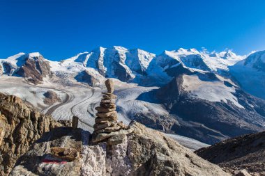Munt Pers 'ın tepesinde, arka planda İsviçre' nin Engadine kentindeki Diavolezza yakınlarında bulunan Piz Palu ve Morteratsch buzulları da dahil olmak üzere Bernina kütlesiyle göz kamaştırıcı bir taş yığını var. Seçici odak.