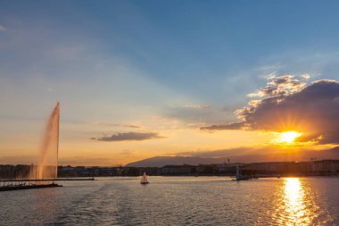 Cenevre Gölü 'ndeki su fıskiyesinin güzel manzarası ve gün batımında Cenevre' nin silueti, İsviçre