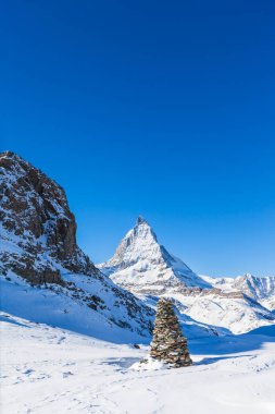 Ünlü Matterhorn 'un kışın yürüyüş yolunda ön planda bir taş yığınıyla görüntüsü, Zermatt, İsviçre