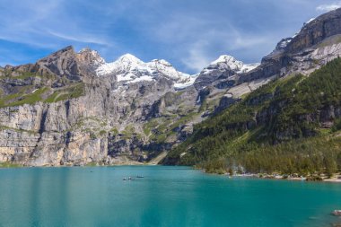 Bernese Oberland 'da Bluemlisalp ve Frundenhorn ile Oeschinensee' nin göz kamaştırıcı manzarası. Fotoğraf yazın İsviçre 'de göl kenarındaki yürüyüş yolunda çekildi.