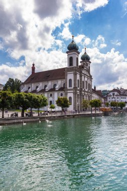 Lucerne Cizvit Kilisesi 'nin (Cizvit Kilisesi) eski Lucerne kasabasındaki Reuss nehri kıyısındaki güzel manzarası, güneşli bir yaz gününde, İsviçre' de mavi gökyüzü bulutu ile yansıtılır.