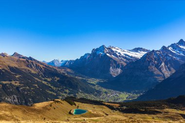 Bernese Oberland 'daki İsviçre Alpleri' nin göz kamaştırıcı manzarası Wetterhorn ve Schrekhorn dahil güneşli bir sonbahar gününde İsviçre 'nin Bern Kantonu' ndan Grindelwald kasabasının manzarası.