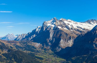 Bern, İsviçre Kantonu Bern 'den açık mavi gökyüzü ile güneşli bir sonbahar gününde Bernese Oberland' da İsviçre Alpleri 'nin Wetterhorn zirvesi olan Grindelwald kasabasının çarpıcı hava manzarası.