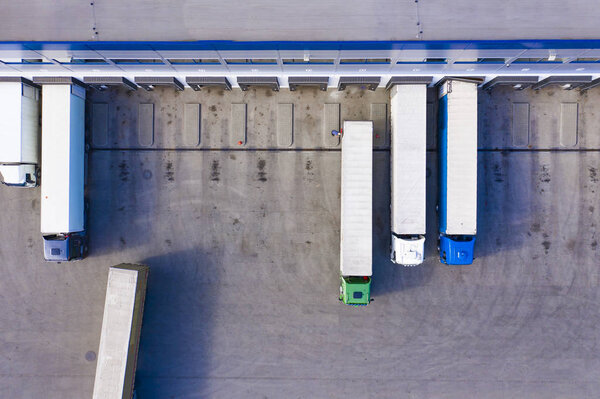 Aerial drone view on logistics center with trucks at the loading