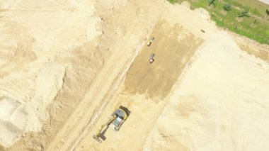 Aerial flight over new constructions site development where heavy machinery and construction workers are working with power tools