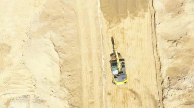 Aerial flight over new constructions site development where heavy machinery and construction workers are working with power tools