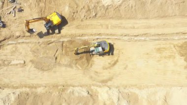 Aerial flight over new constructions site development where heavy machinery and construction workers are working with power tools