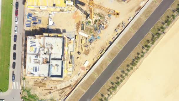 Aerial flight over new constructions site development where heavy machinery and construction workers are working with power tools — Αρχείο Βίντεο