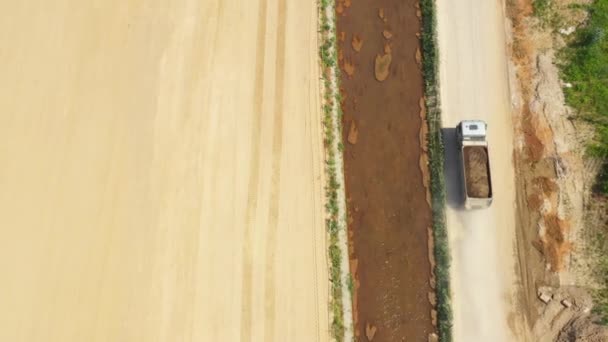 Dömper kamion homokkal folyik, áthaladva autópálya építési oldalon. Légifelvétel — Stock videók