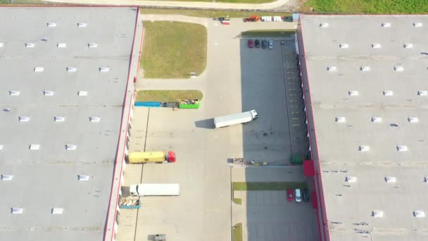 Vista aérea del almacén de mercancías. Centro logístico en zona industrial de ciudad desde arriba. Vista aérea de camiones cargando en el centro logístico — Vídeo de stock