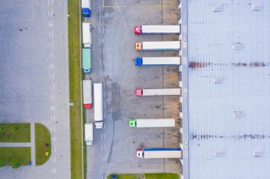 Malzeme deposunun havadan görüntüsü. Sanayi bölgesindeki lojistik merkezi yukarıdan. Lojistik merkezde yüklenen kamyonların hava görüntüsü. İnsansız hava aracından görüntüle.
