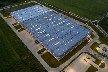 Gece vakti büyük lojistik parkının havadan aşağı görüntüsü, yükleme / boşaltma malları için rampalarda bekleyen kargo karavanları taşıyan kamyonlarla dolu bir merkez.