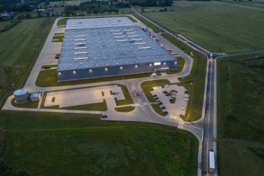 Gece vakti büyük lojistik parkının havadan aşağı görüntüsü, yükleme / boşaltma malları için rampalarda bekleyen kargo karavanları taşıyan kamyonlarla dolu bir merkez.