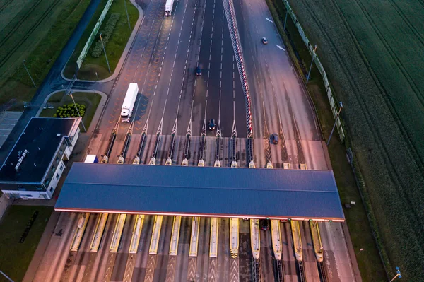 Car traffic transportation on multiple lanes highway road and toll collection gate, drone aerial top view at Night. Commuter transport, city life concept.A2 Poland Lodz