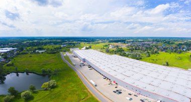 Çatıda güneş panelleri ve birçok kamyonla Endüstriyel Depolama Alanının Havadan Üst Görünümü.