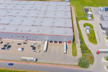 Çatıda güneş panelleri ve birçok kamyonla Endüstriyel Depolama Alanının Havadan Üst Görünümü.