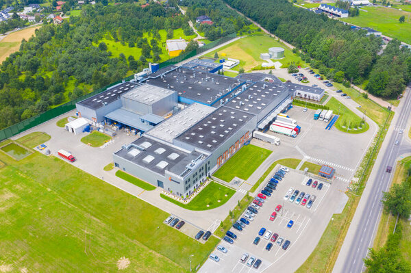 Aerial Top View of Industrial Storage Building Area with Solar Panels on the Roof and Many Trucks Unloading Merchandise.