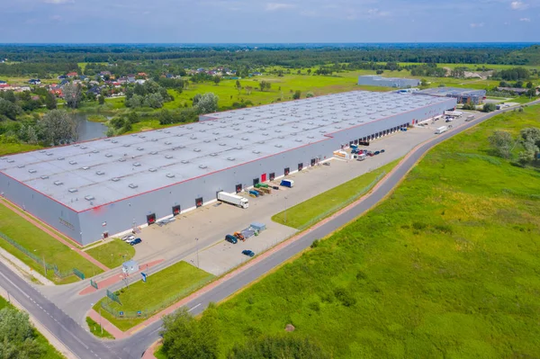Aerial drone on trucks and logistic center. Warehouse aerial. Modern logistics center, white van and trailers standingon ramp.