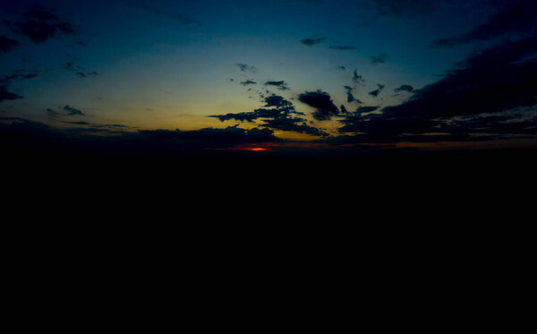 Panoramic aerial view of beautiful green tropical forest with mountains and majestic blue sky and clouds. Sunset