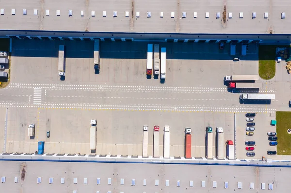 Aerial Shot of Industrial Warehouse Loading Dock where Many Truck with Semi Trailers Load Merchandise.