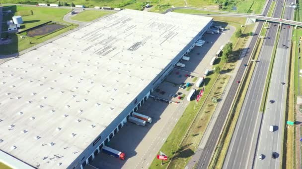 Vista aérea del almacén de mercancías. Centro logístico en zona industrial de ciudad desde arriba. Vista aérea de camiones cargando en el centro logístico. Vista desde el dron. — Vídeo de stock